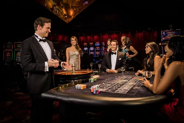 A professional dealer in a tuxedo greeting players at the roulette table, symbolizing the authentic live casino feel at 866JL.